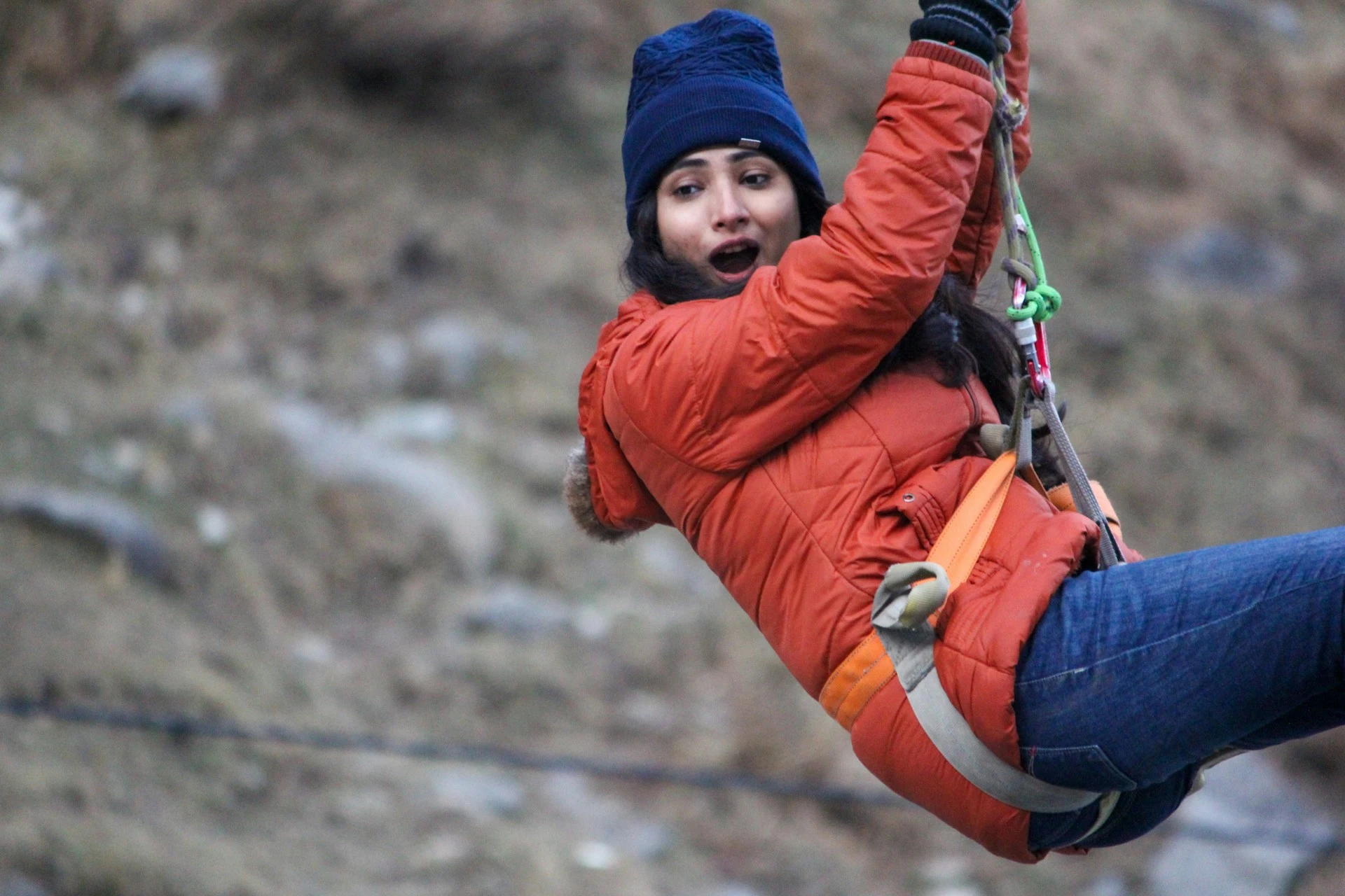woman in winter gear in harness attached to zipline with carabiner set up